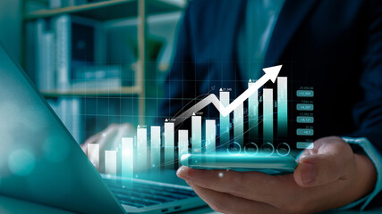 A businessman analyzes financial growth using a smartphone and laptop, with a rising bar chart and...