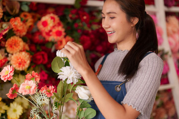Asian woman florist happily arranging colorful flower designs at vibrant flower shop professional...