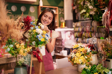 Adult Asian woman happily working creating flower bouquets inside a beautiful bloom retail store