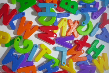 Fototapeta premium Colorful Plastic Alphabet Letters Spread Out on a White Surface