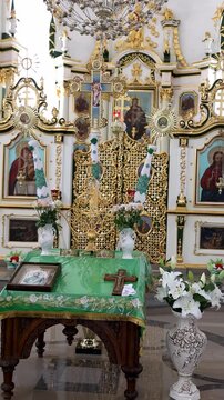 Interior of a modern Orthodox church with an iconostasis, throne and banners.