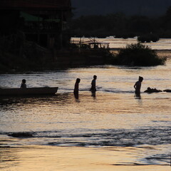 shadows of children playing in the water in the evening