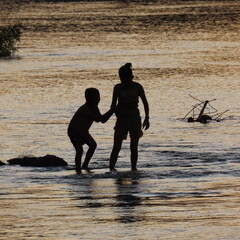 shadows of children playing in the water in the evening