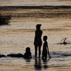 shadows of children playing in the water in the evening