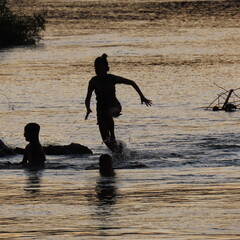 shadows of children playing in the water in the evening