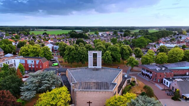 Approaching the belfry with three bells on the church. Picturesque residential area around. The Netherlands. Aerial view.