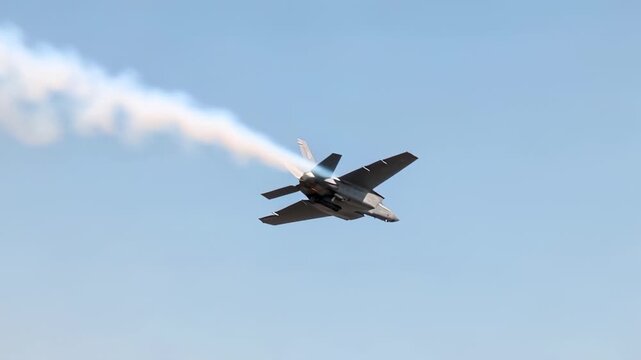 Modern fighter jet performing a high-speed maneuver against a clear bl