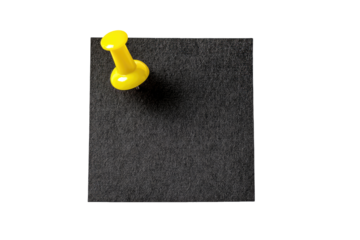 A bright yellow pushpin is affixed to a dark gray square memo pad