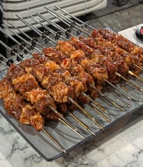 Close-up of juicy marinated beef skewers on metal grill sticks, prepared for barbecue, street food concept