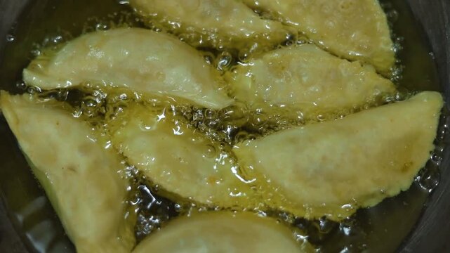 Gujhiya a dessert being crispy fried in oil