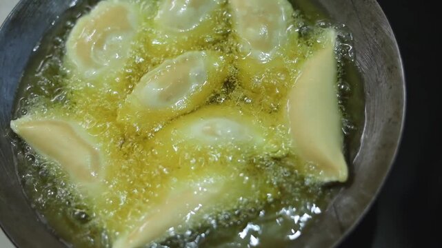 Gujhiya a dessert being crispy fried in oil