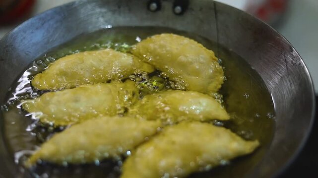 Gujhiya a dessert being crispy fried in oil