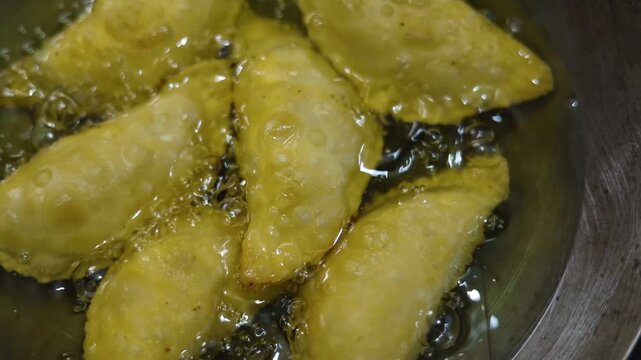 Gujhiya a dessert being crispy fried in oil