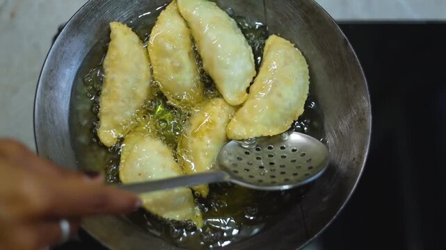 Gujhiya a dessert being crispy fried in oil