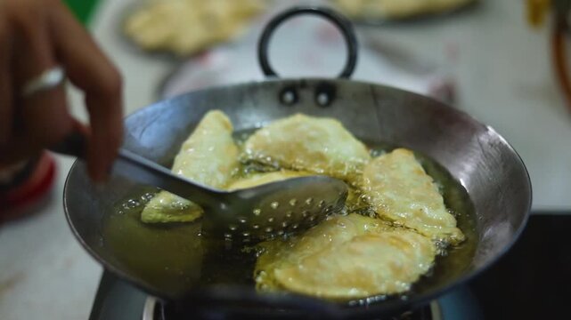 Gujhiya a dessert being crispy fried in oil