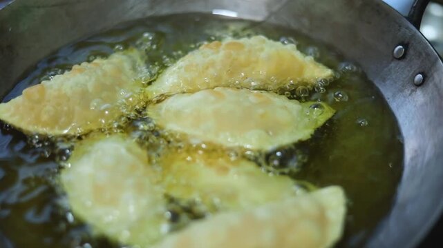 Gujhiya a dessert being crispy fried in oil