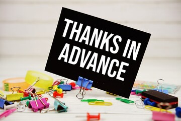 Thanks In Advance text on paper card with stationary on wooden background