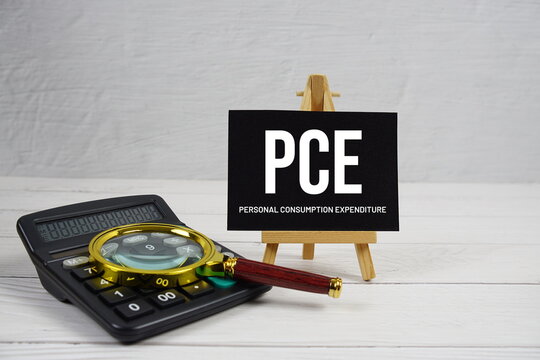 PCE abbreviation of Personal Consumption Expenditure text with magnifying glass and calculator on wooden background