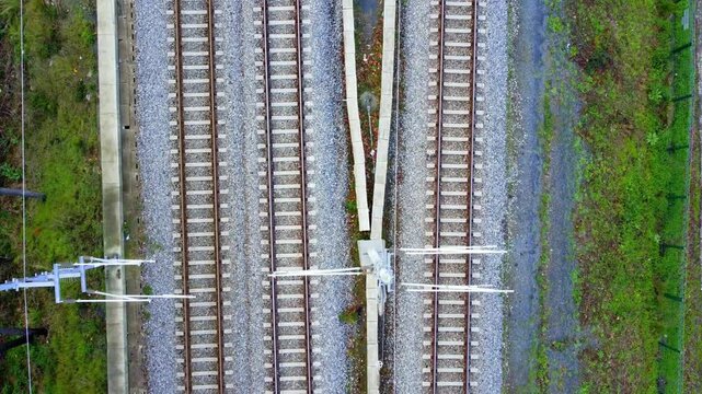 Aerial Top-Down View of Twin Railroad Tracks Cutting Through Green Landscape