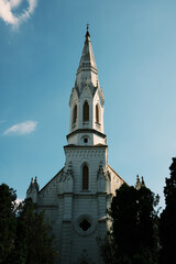 White gothic-style church tower with detailed spire and cross in Zrenjanin, Serbia. Bright sky and architectural contrast enhance the historic feel of the landmark.
