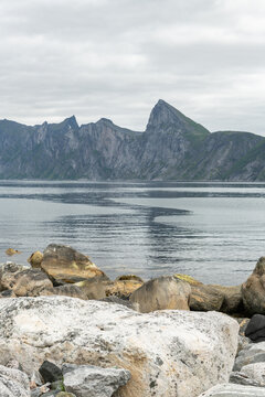 Medjorden view with Segla and Hesten mountain in the background. Big rocks, bolders in the foreground. Cloudy summer day in july. Amazing wild nature in arctic Norway on Senja island.