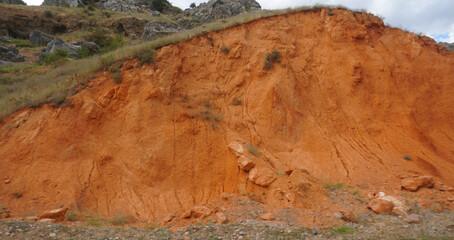 The eroded hill at the edge of the mountain road is red