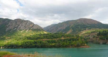 The sunlight falls on the green mountain by the river.