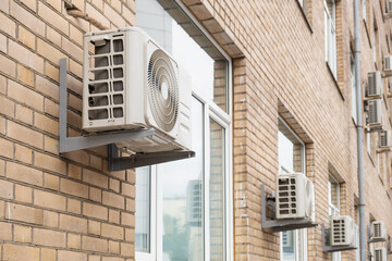 Close-up of external AC units mounted on the wall of a modern brick building, showing details of...