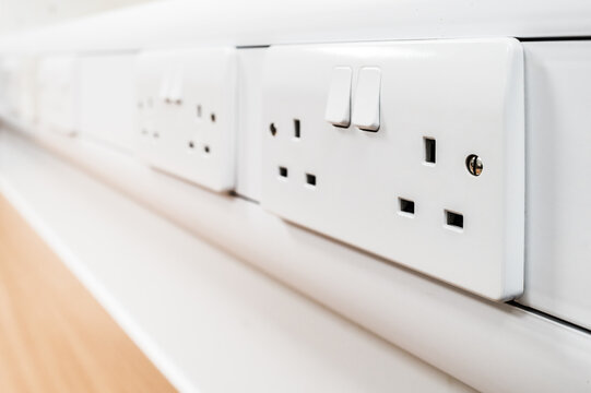 Shallow focus of newly fitted switchable 240 volt electrical sockets seen on a desk in a new office. Used for hot desking.