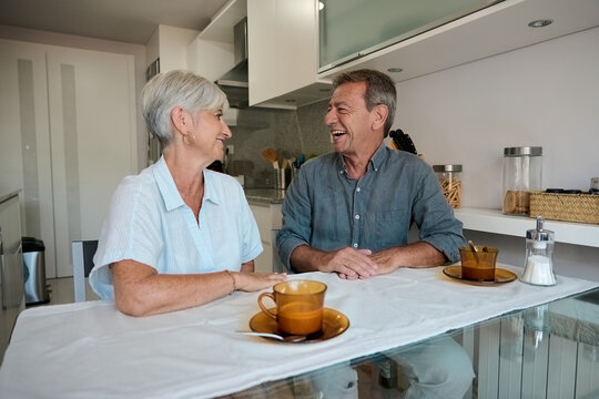 Happy senior couple enjoying coffee and conversation in kitchen