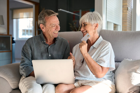 Happy senior couple shopping online using laptop and credit card at home