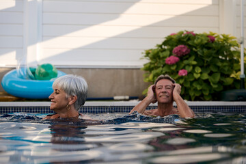 Senior couple relaxing and enjoying swimming pool in summer