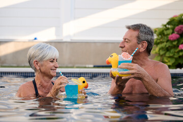 Senior couple enjoying cocktails in swimming pool