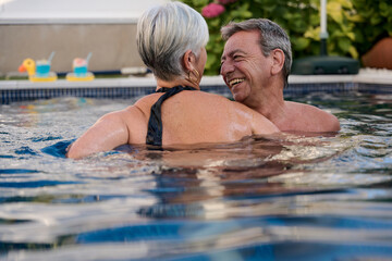 Happy senior couple enjoying swimming pool on summer vacation