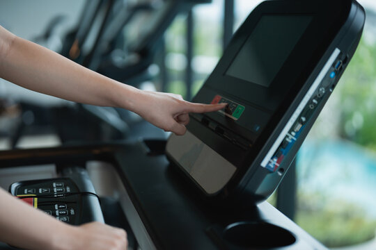Close-up of a hand using digital control panel on a treadmill in a modern gym setting during a fitness workout session for health enthusiasts