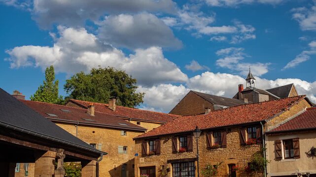 Scenic view of rustic stone houses with red-tiled roofs in Torgny, Belgium. Bright blue sky with fluffy clouds adds charm to this picturesque village in the Gaume region.