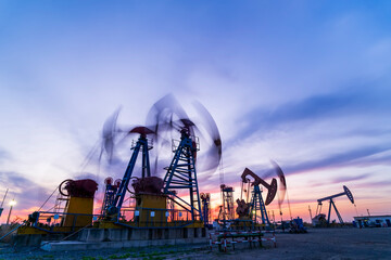 in the evening, oil pumps are running, The oil pump and the beautiful sunset reflected in the water, the silhouette of the beam pumping unit in the evening.