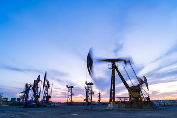 in the evening, oil pumps are running, The oil pump and the beautiful sunset reflected in the water, the silhouette of the beam pumping unit in the evening.