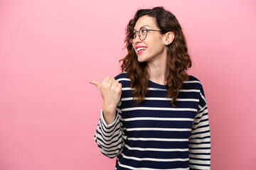 Young caucasian woman isolated on pink background pointing to the side to present a product