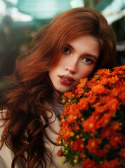 Portrait Beautiful red-haired young woman with a bouquet of autumn chrysanthemum flowers at the city flower market.