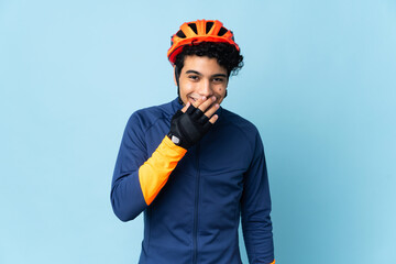 Venezuelan cyclist man isolated on blue background happy and smiling covering mouth with hand