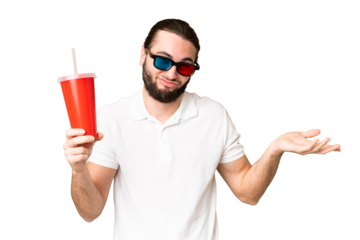 Young handsome man holding soda while watching a 3D movie over isolated chroma key background making doubts gesture while lifting the shoulders