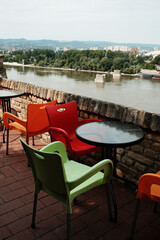 Colorful plastic chairs on a terrace outdoor cafe overlooking the Danube River in Petrovaradin Fortress, Novi Sad, Serbia.