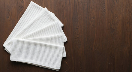 Stack of white paper napkins fanned out on a dark wooden surface