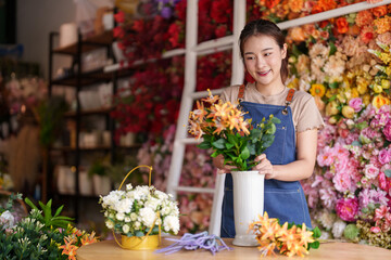 Asian small business owner arranging artificial flowers in vibrant floral shop creating stunning...