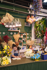 Asian adult woman florist manages orders talks phone writes notebook at busy flower shop arranging...
