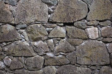 Detailed texture of an ancient, weathered castle stone wall, showcasing rough, rugged masonry. Ideal historical background or backdrop