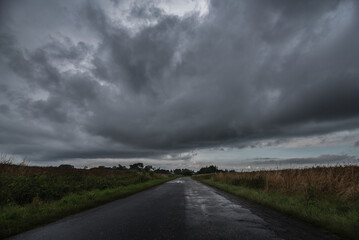 
WEATHER - Dramatic black rain clouds over fields and country road
