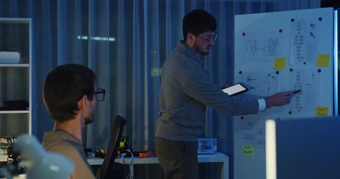 Team adult male engineer develop present AI robotics hand project at tech workspace night. Artificial intelligence, collaboration support prototype development, robotic, machine learn, training.