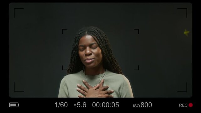 CAM view of young African American actress looking at camera and performing touching monologue against gray background